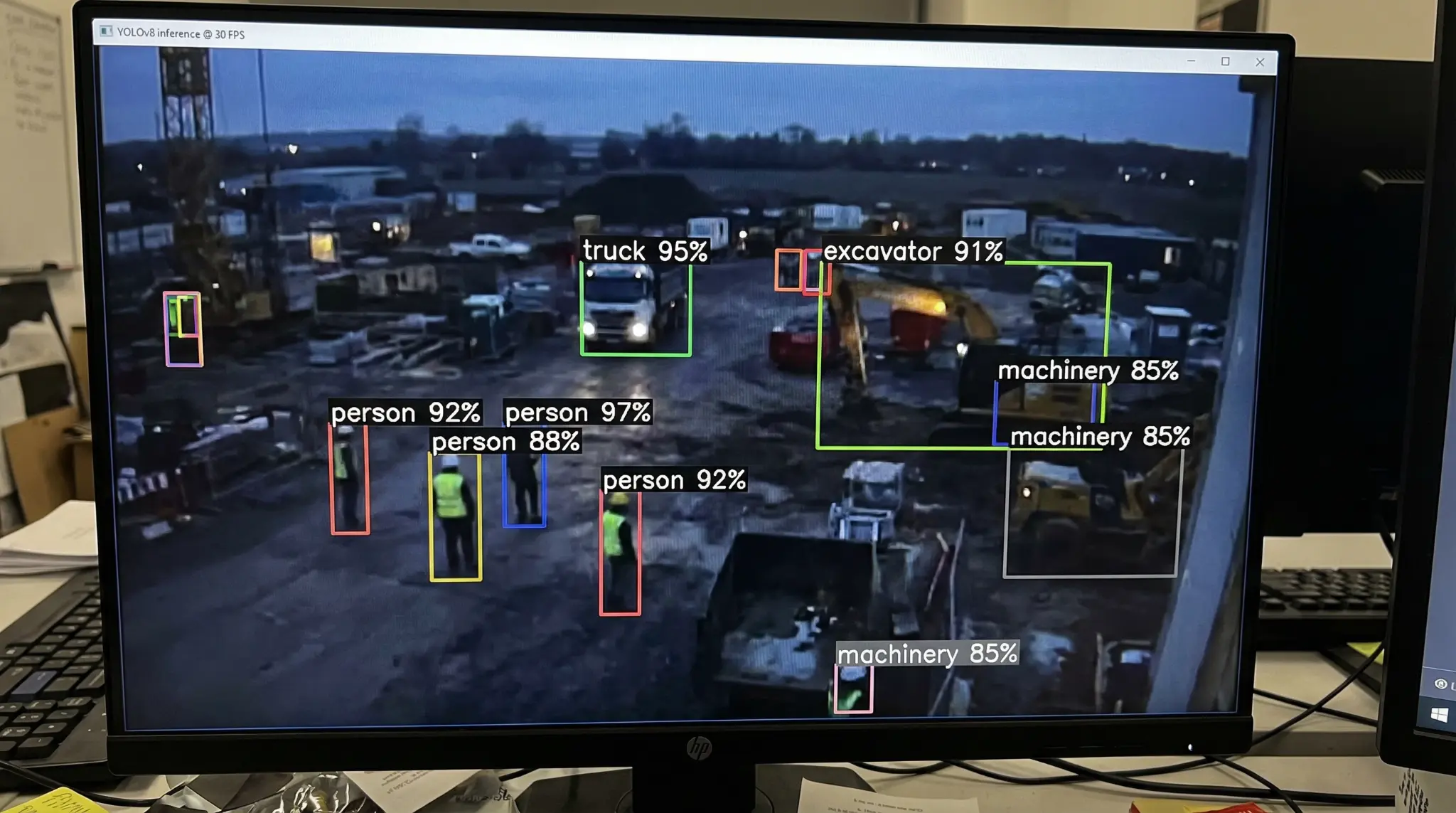 Computer vision interface showing YOLO detections on machinery and workers.